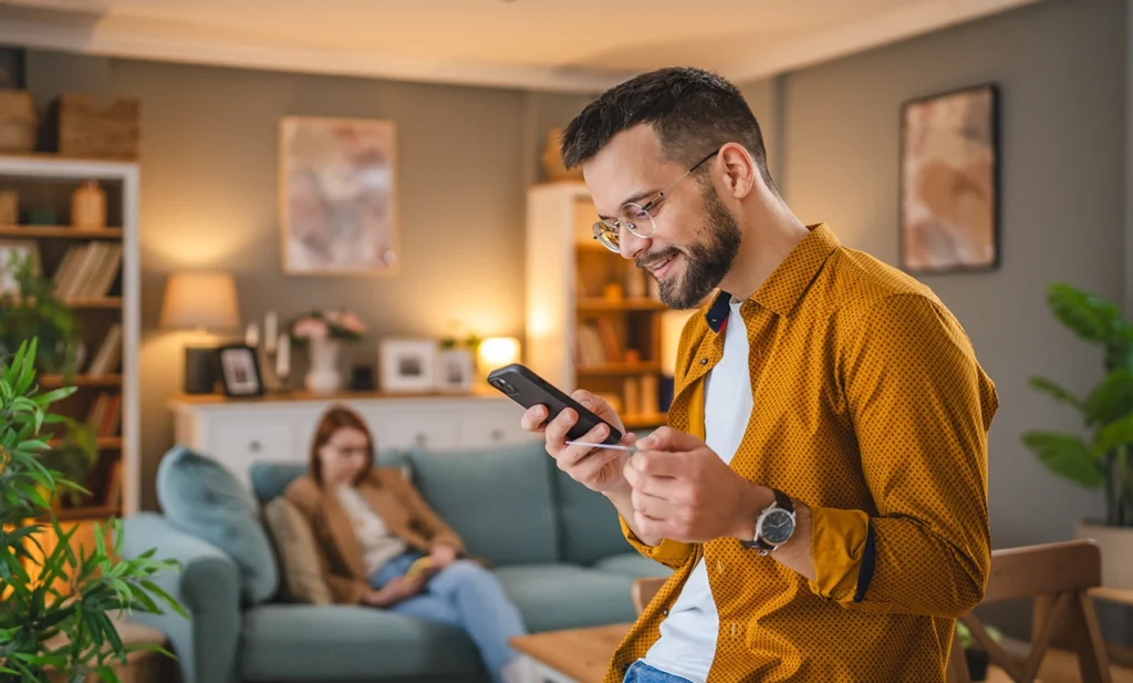 Gestione finanze personali: ragazzo sorridenti in piedi guarda smartphone