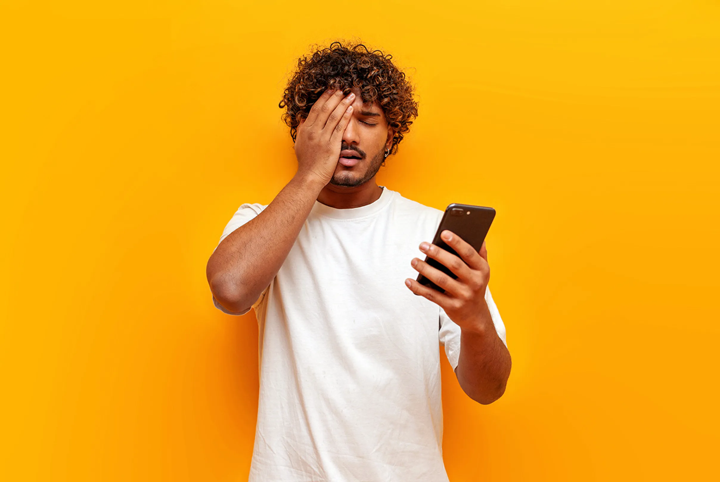 Ragazzo guarda smartphone e si dispera per rinnovo abbonamenti