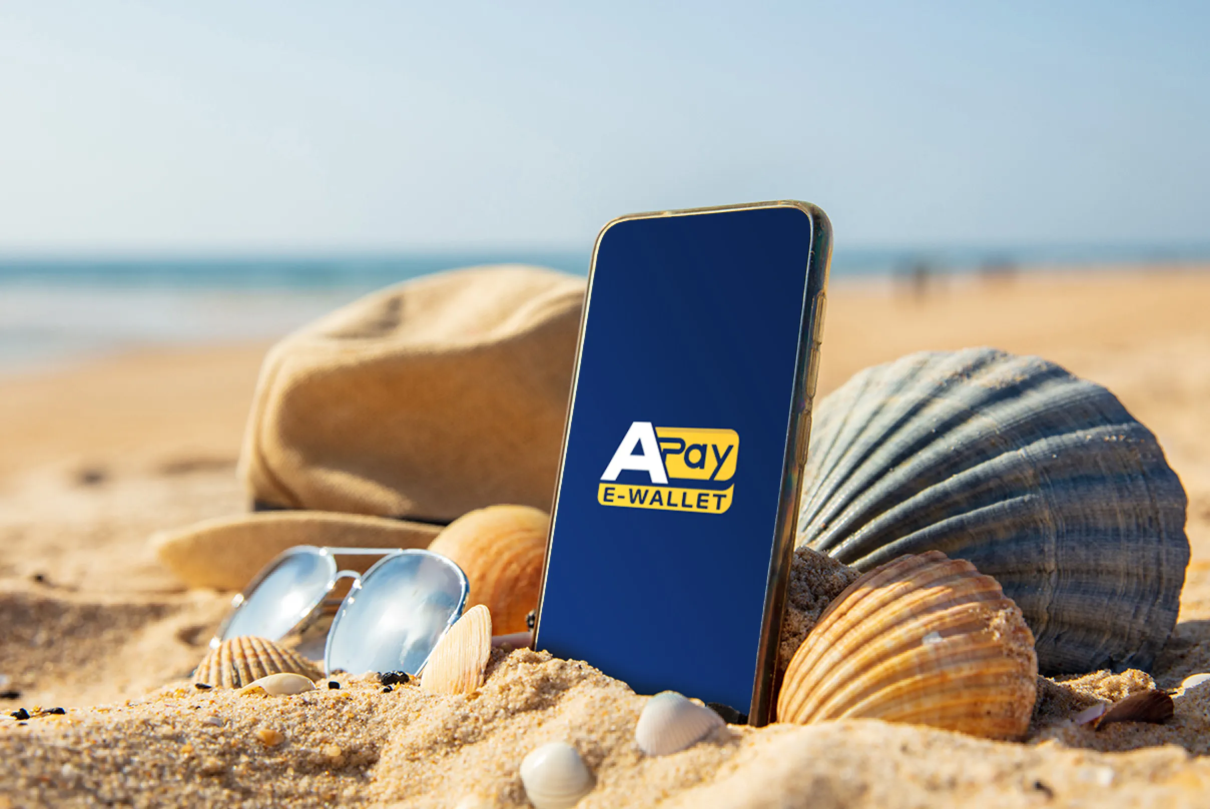 Smartphone con APay E-Wallet sulla spiaggia, simbolo dei pagamenti digitali in viaggio per gestire spese e acquisti in vacanza in modo semplice e sicuro.